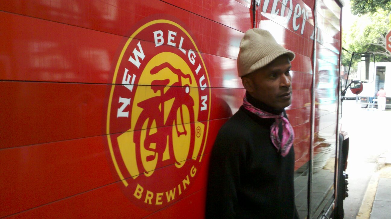 AIDS/Lifecycle Cyclist stands beside New Belgium Brewing Company Logo.